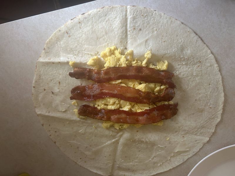 Lefse with scrambled eggs and bacon being prepared for wrap