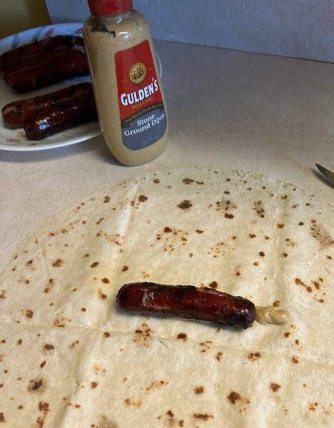 Assembling lefse brat with mustard and bratwurst