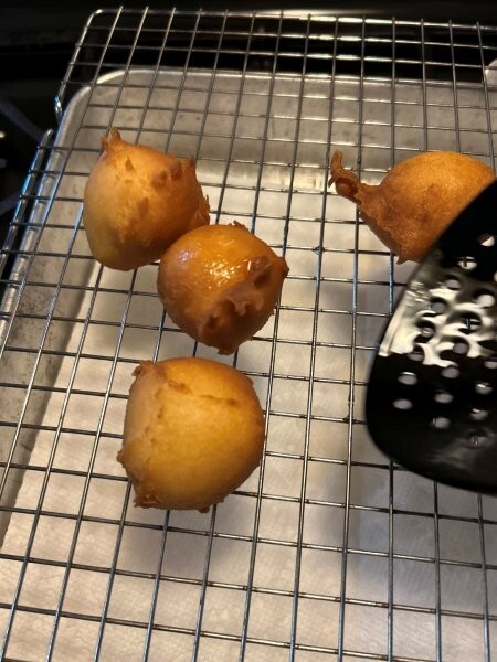 Donut holes cooling on rack after frying