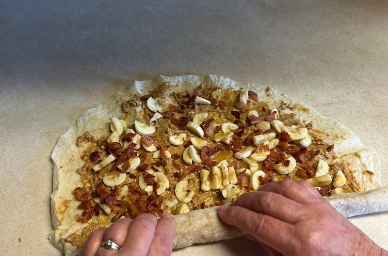 Rolling the Elvis lefse into a cylinder and slicing into four pieces