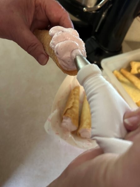 Filling krumkake cone with lingonberry whipped cream