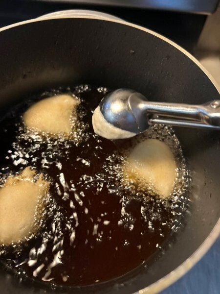 Dropping donut batter into hot oil using scoop