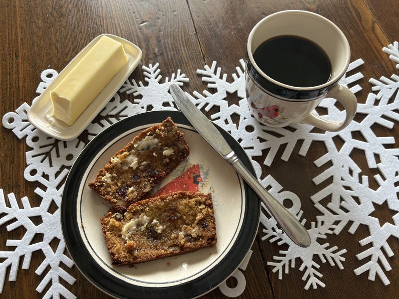 Sliced Gjetost quick bread served with butter and a cup of coffee