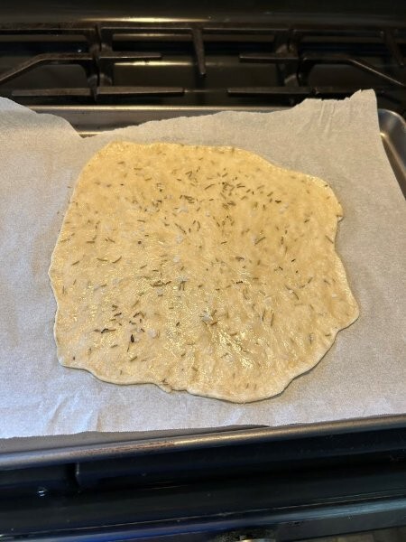Flatbread oiled and additional rosemary and seas salt sprinkled on it—ready for the oven.