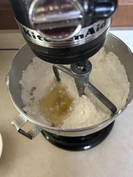 Mixing almond flour, powdered sugar, egg whites, and extracts to form dough for kransekake