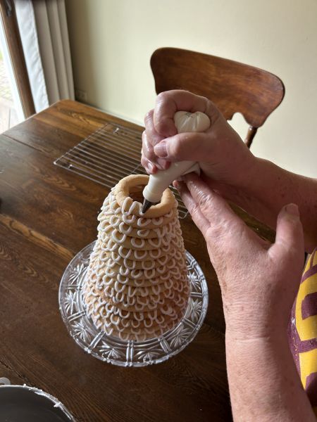 Adding final rings and piping icing on kransekake