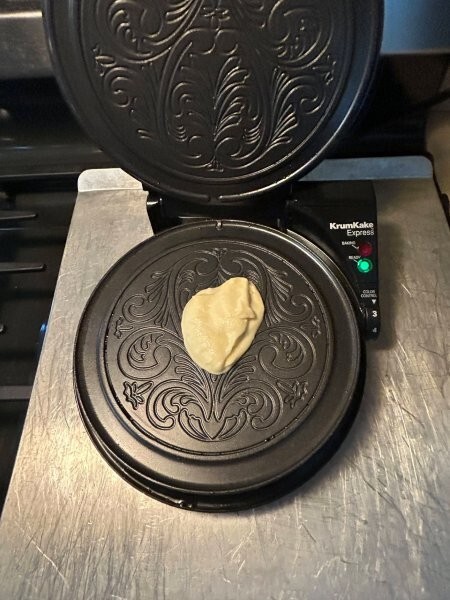 Krumkake batter on iron ready to bake