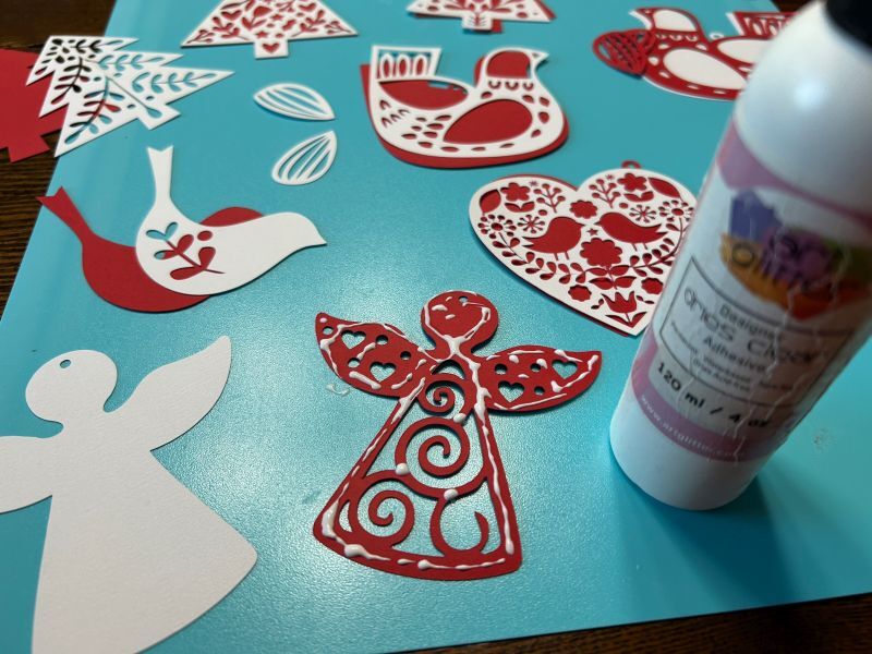 Applying fine-tip glue to assemble layered Norwegian paper ornaments.