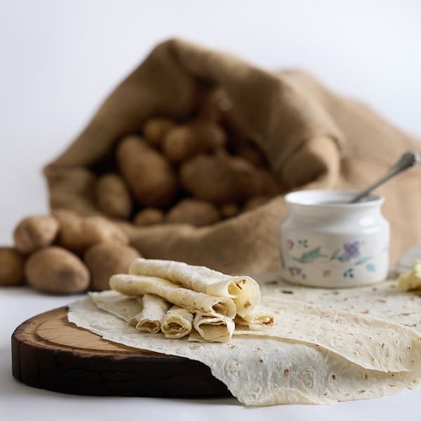 Fresh Norsland Lefse on a board with potatoes in the background