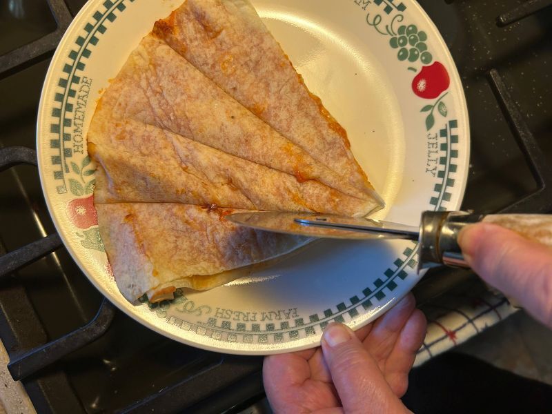 Slicing cooked lefse pizza dippers with a pizza cutter