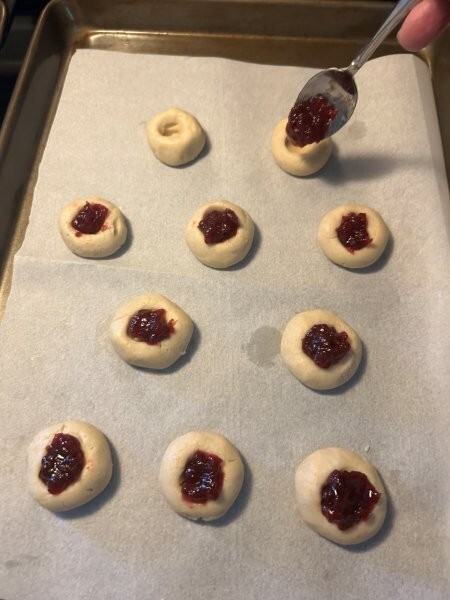 Adding the preserves to the thumbprint cookies. Do not overfill!