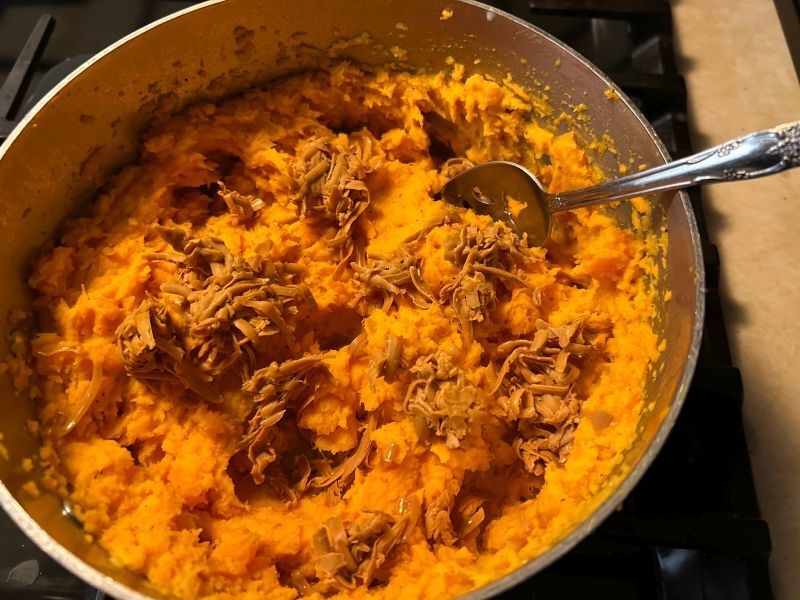 Mashing sweet potatoes and mixing in Gjetost cheese