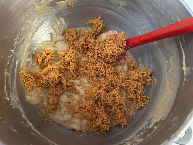 Folding grated Gjetost cheese into quick bread batter in bowl