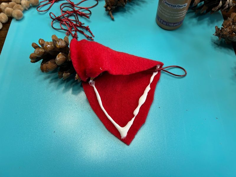 Felt hat wrapped around the pinecone with the hanging cord tucked inside.