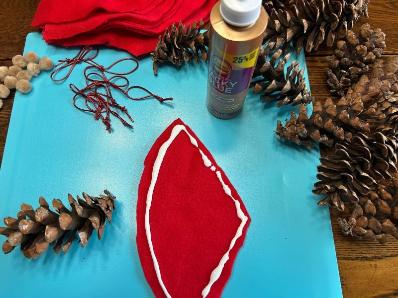 Cone-shaped red felt being glued to prepare the hat for a pinecone gnome ornament.