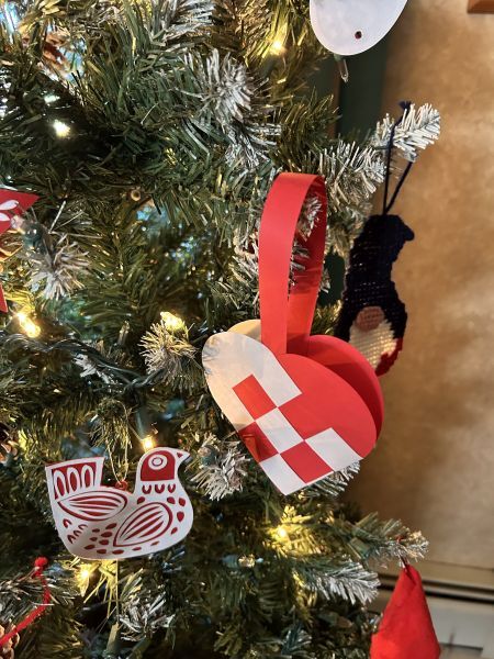 Scandinavian woven heart ornament hanging on a Christmas tree.