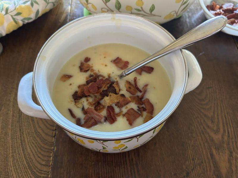 Serving potato soup topped with bacon and crushed lefse chips