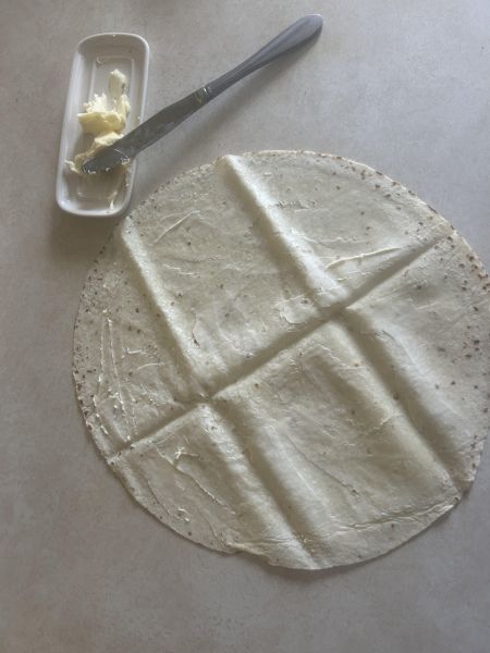 Spreading butter on a round of lefse for breakfast wrap preparation