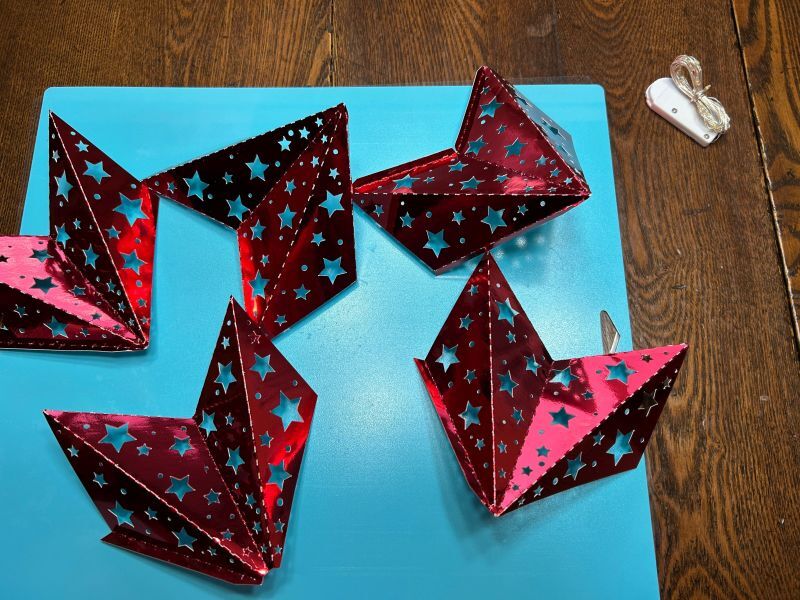 Cut cardstock pieces folded on score lines for assembling a Scandinavian paper star tree topper.