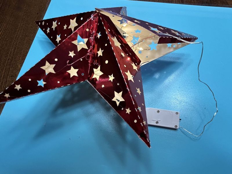 Gluing the points together and adding battery-powered fairy lights to the paper star tree topper.