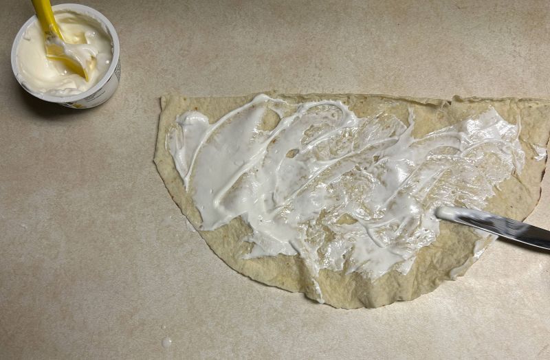 Spreading coconut vanilla yogurt on a half round of lefse