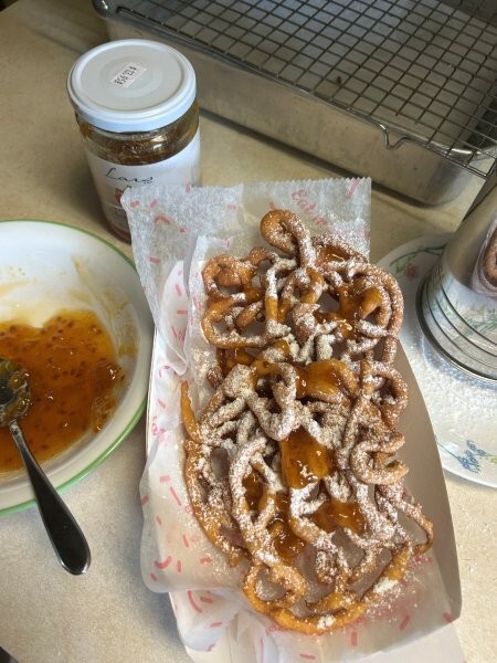 Drizzling cloudberry preserves on powdered funnel cake