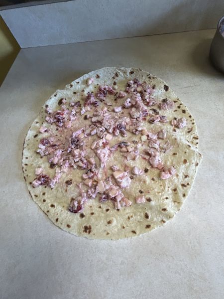 Rolled lefse wrap with turkey cranberry filling, sliced in half.