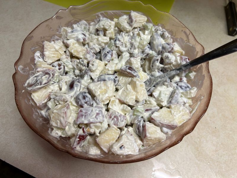 Mixing mayonnaise and sour cream dressing into Waldorf salad